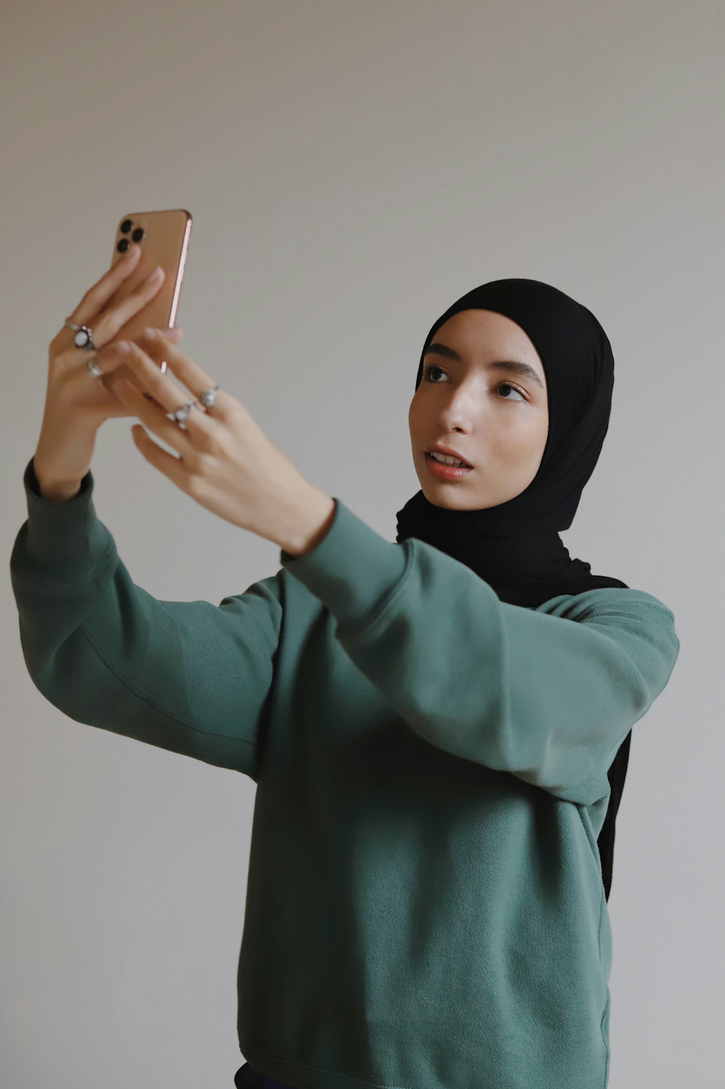 woman in green long sleeved shirt holding silver iphone 6